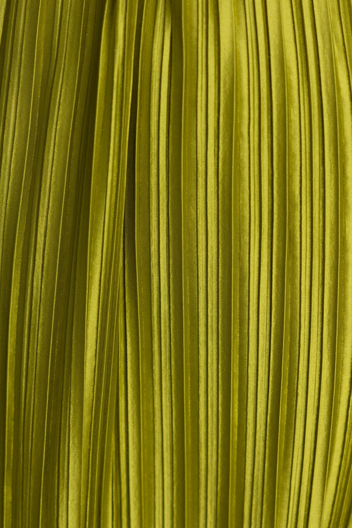Close-up of accordion pleats in a vibrant green fabric, showcasing satin texture and shine.