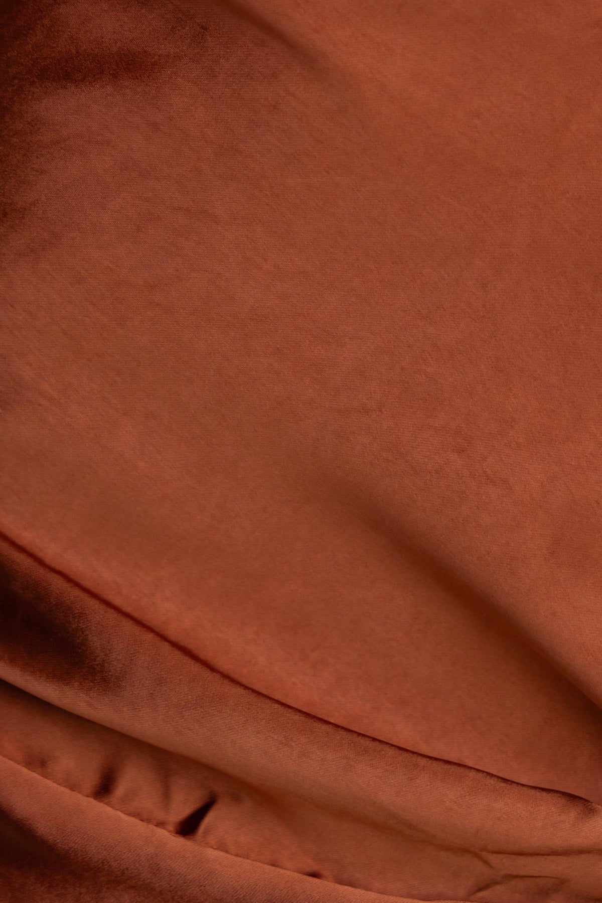 Close-up of Yasie Maxi Skirt fabric highlighting its rich, satin-like orange texture and smooth finish.