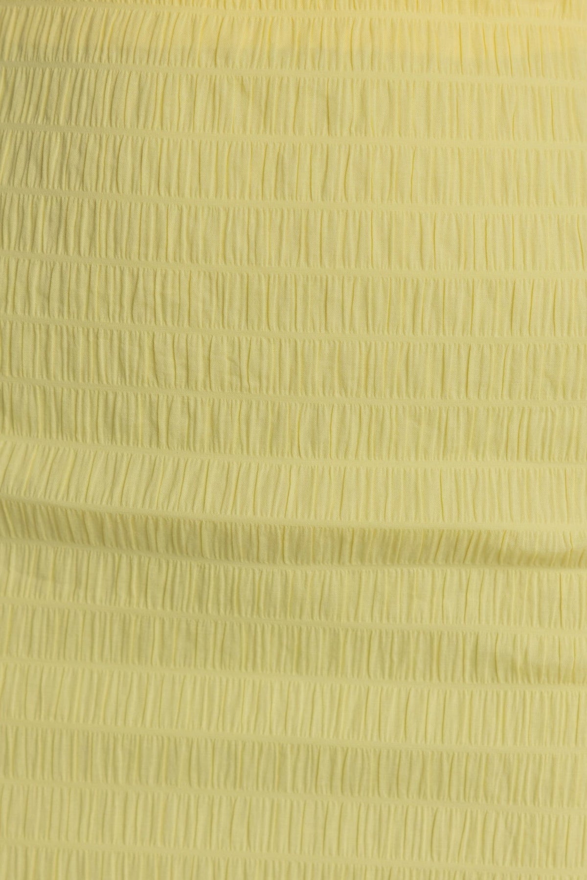 Close-up of Tinkie Skirt in soft yellow fabric with textured smocking for a comfortable and stylish fit.