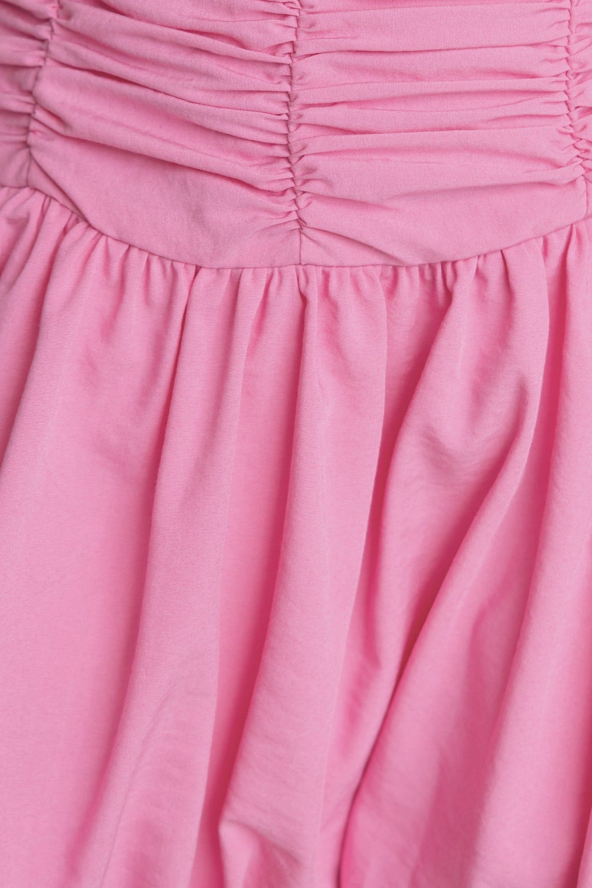 Close-up of Margie Dress showing ruching details and flowing pink fabric, designed for a standard fit, perfect for casual outings.