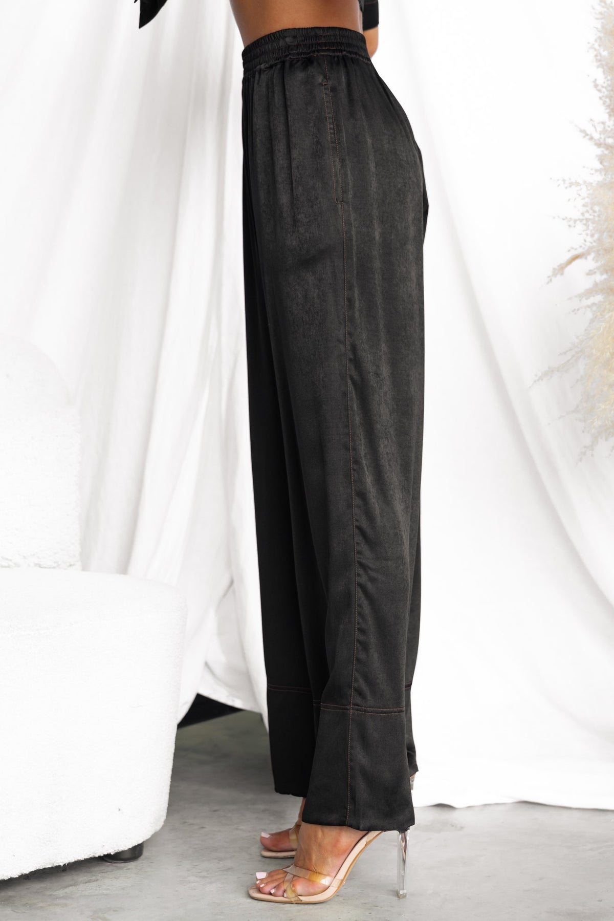 Side view of Noel Pants, black mid-high waist trousers with elastic waistband and pockets.