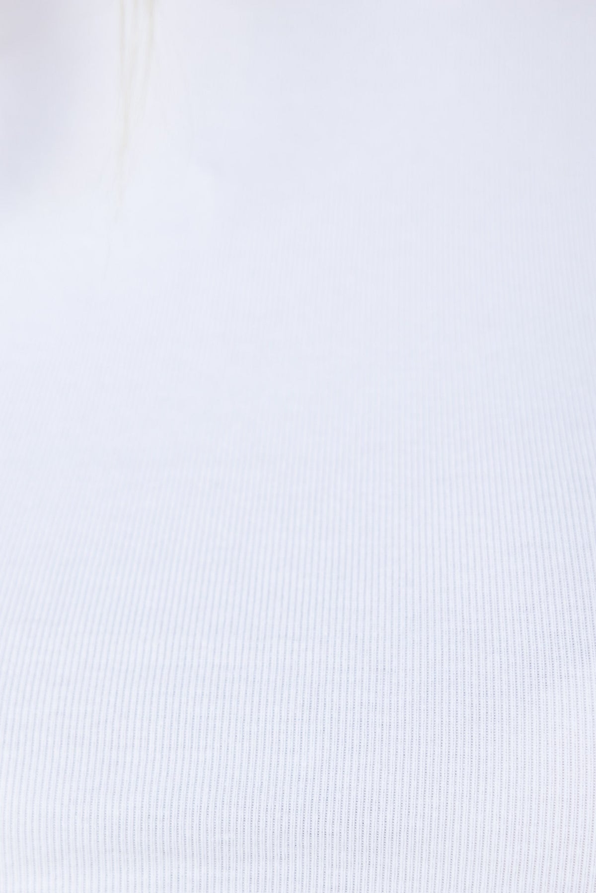 Close-up of Nelly Top in soft white cotton, showcasing a smooth, stretchy ribbed texture.