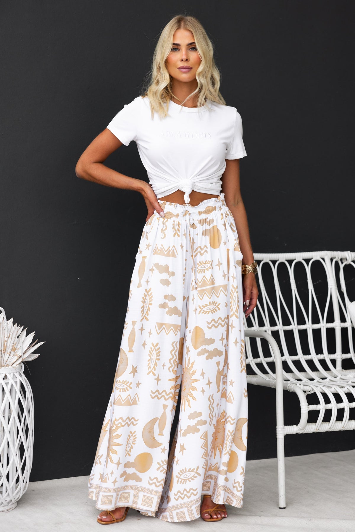 Model wearing Amadi Pants with abstract print, mid-high waist, and wide legs, styled with a cropped white top.
