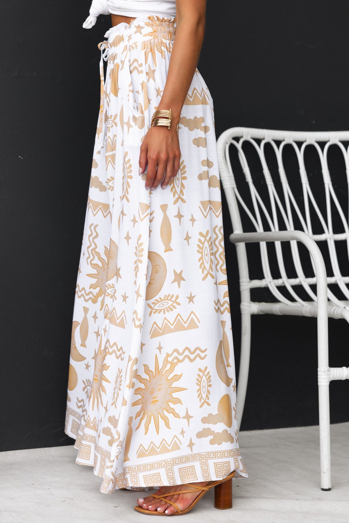 Amadi Pants featuring abstract print, mid-high waist, elastic waistband with drawstring, and wide legs in white and gold.
