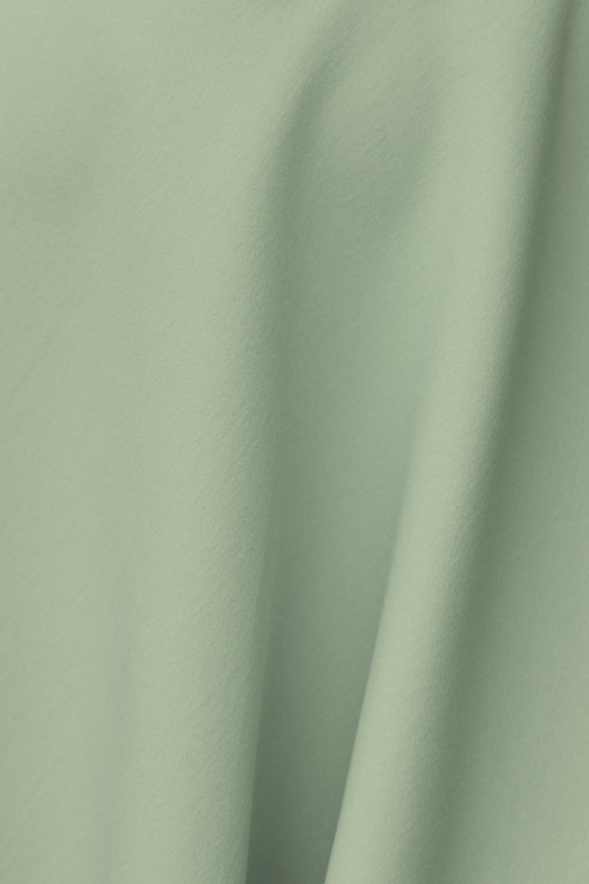 Close-up of soft green fabric showcasing smooth texture, ideal for elegant dresses and light garments.