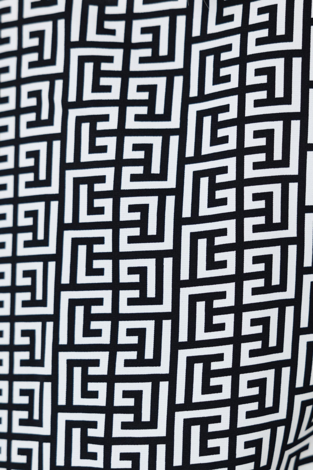 Close-up of abstract geometric print in black and white on fabric, showcasing intricate pattern details.