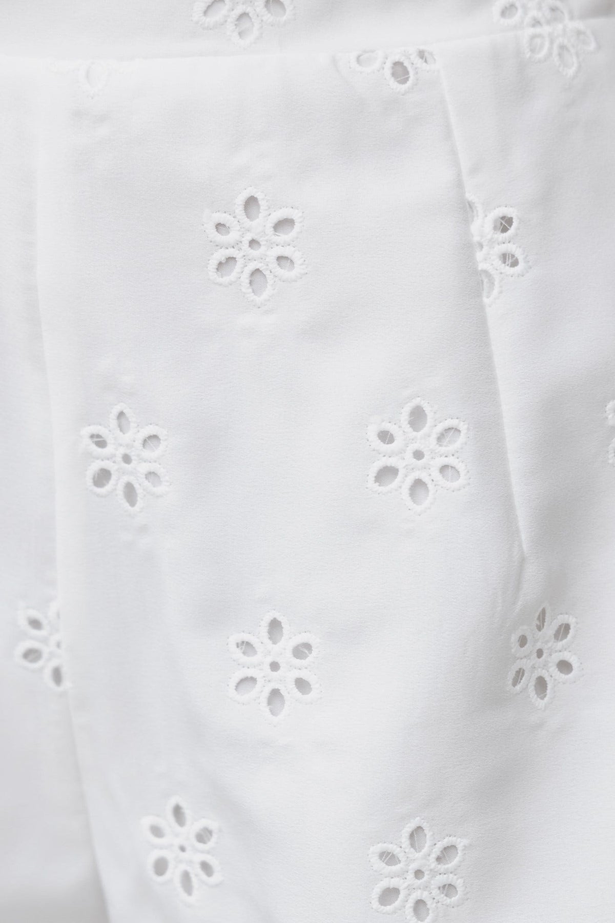 Close-up of white Koa Shorts featuring intricate lace details and flower pattern for a stylish summer look.