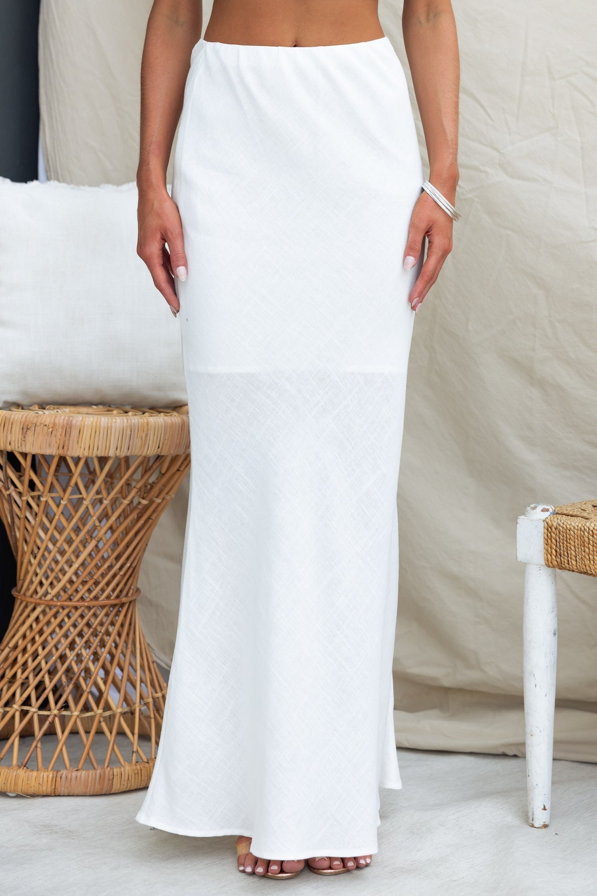 Elegant white maxi skirt featuring a mid-high waist and elastic waistband, styled for a chic summer look.
