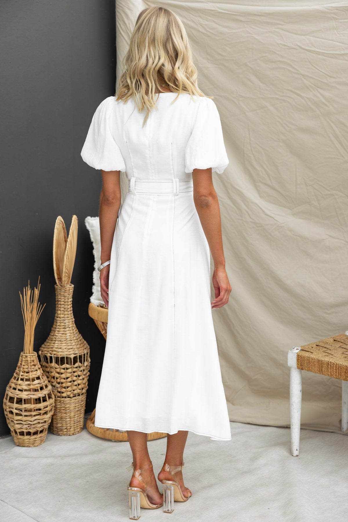 Back view of a woman in a white Orderly Midi Dress with puff sleeves and a removable fabric tie.