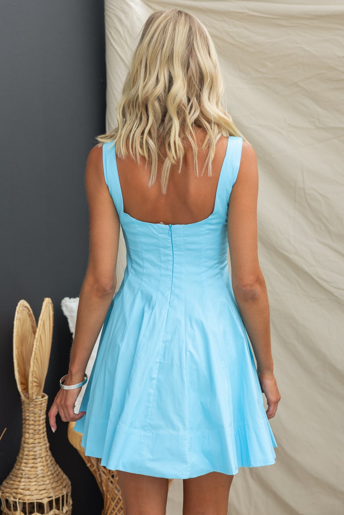 Back view of a woman in a blue Sincerity Dress with a square neckline and invisible zip, showcasing a flared skirt.