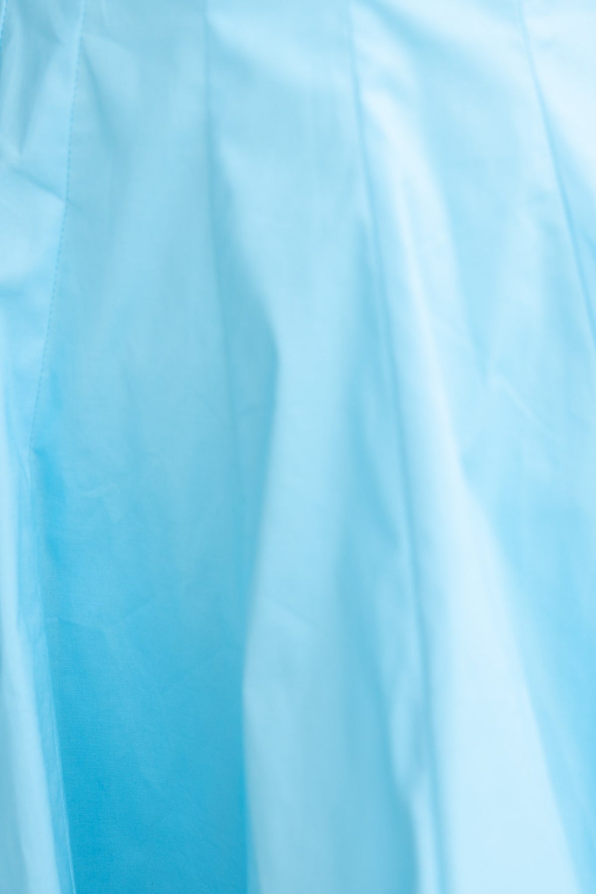 Light blue dress fabric with pleats, showcasing soft texture and color gradient.