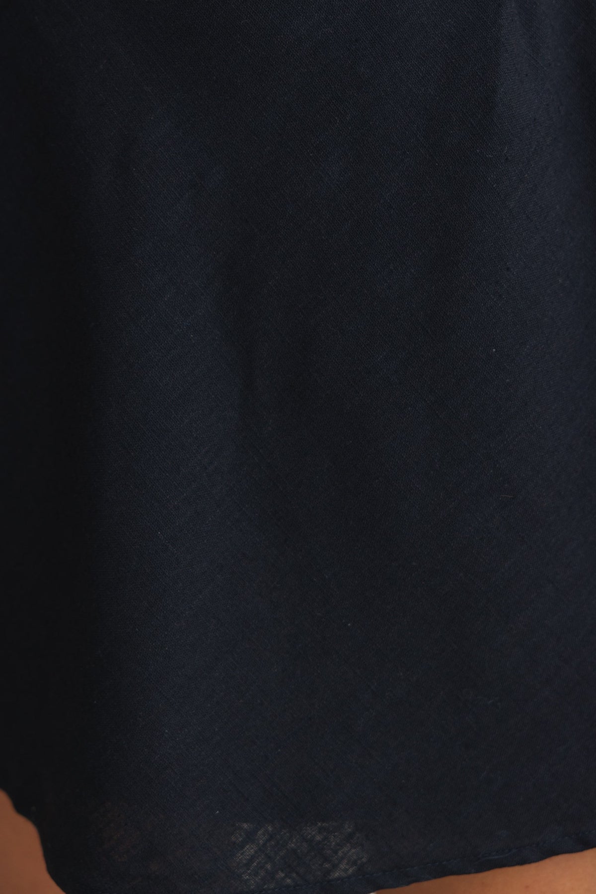 Close-up of the Rania Dress showcasing the textured black cotton fabric and elegant draping.
