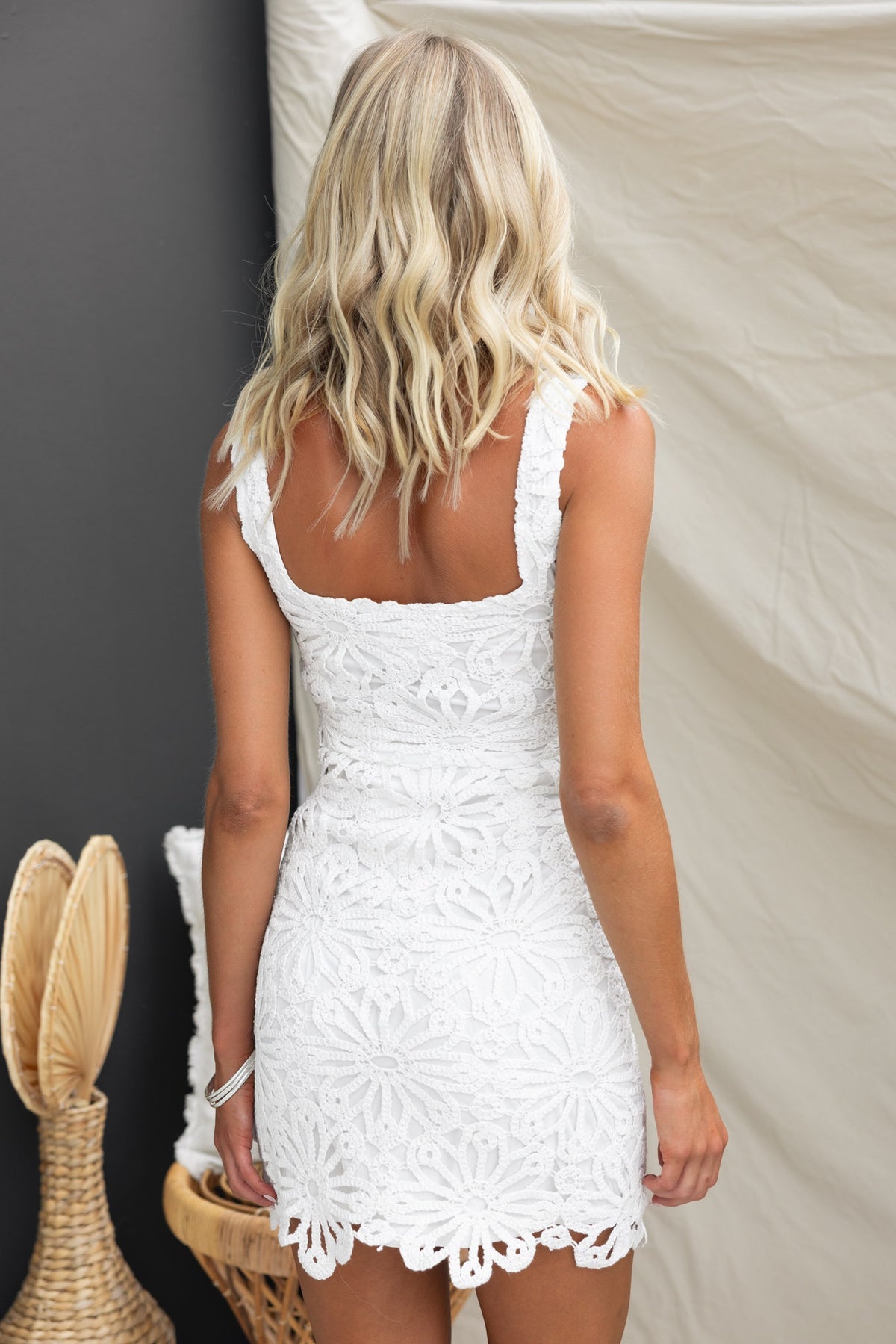 Back view of the white Musa dress showcasing crochet floral design and square neckline style.