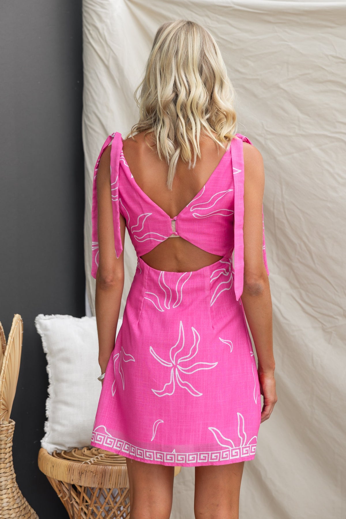 Back view of the Malina Dress, featuring a pink floral print, adjustable tie straps, and cut-out design.