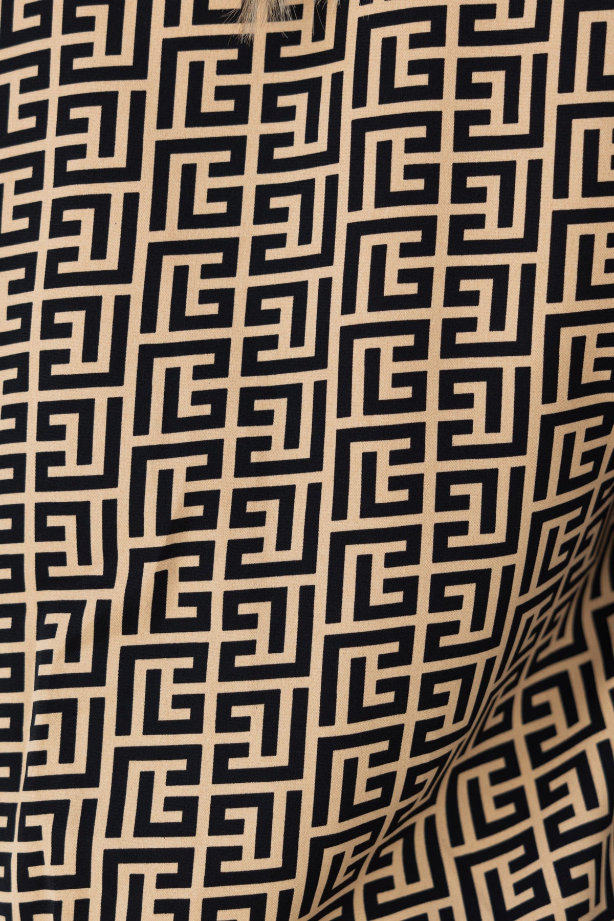 Close-up of abstract print fabric featuring geometric patterns in black and beige, ideal for stylish pants or apparel.