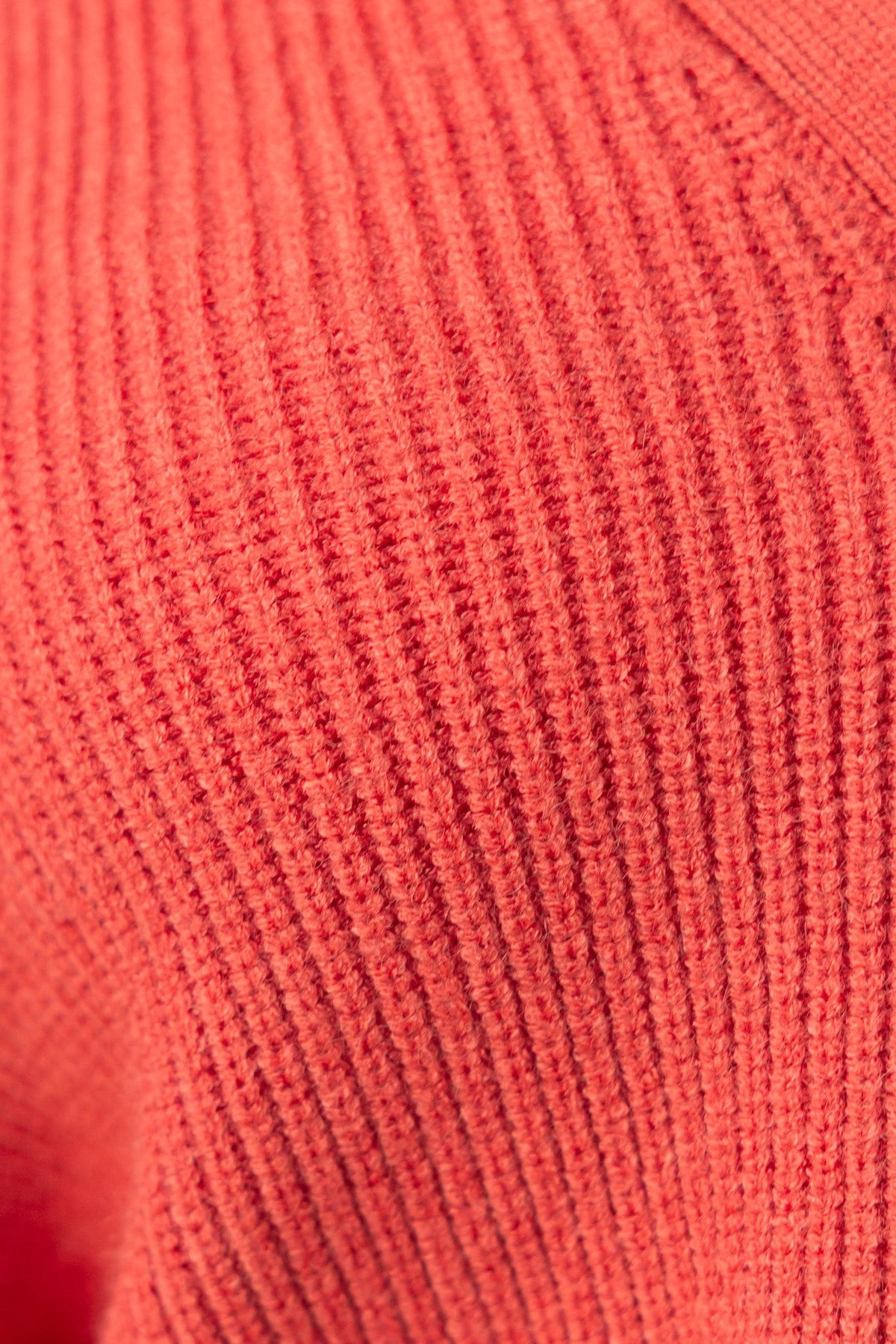 Close-up of the ribbed knit fabric of a coral Modalla Cardigan, showcasing its texture and stretch.