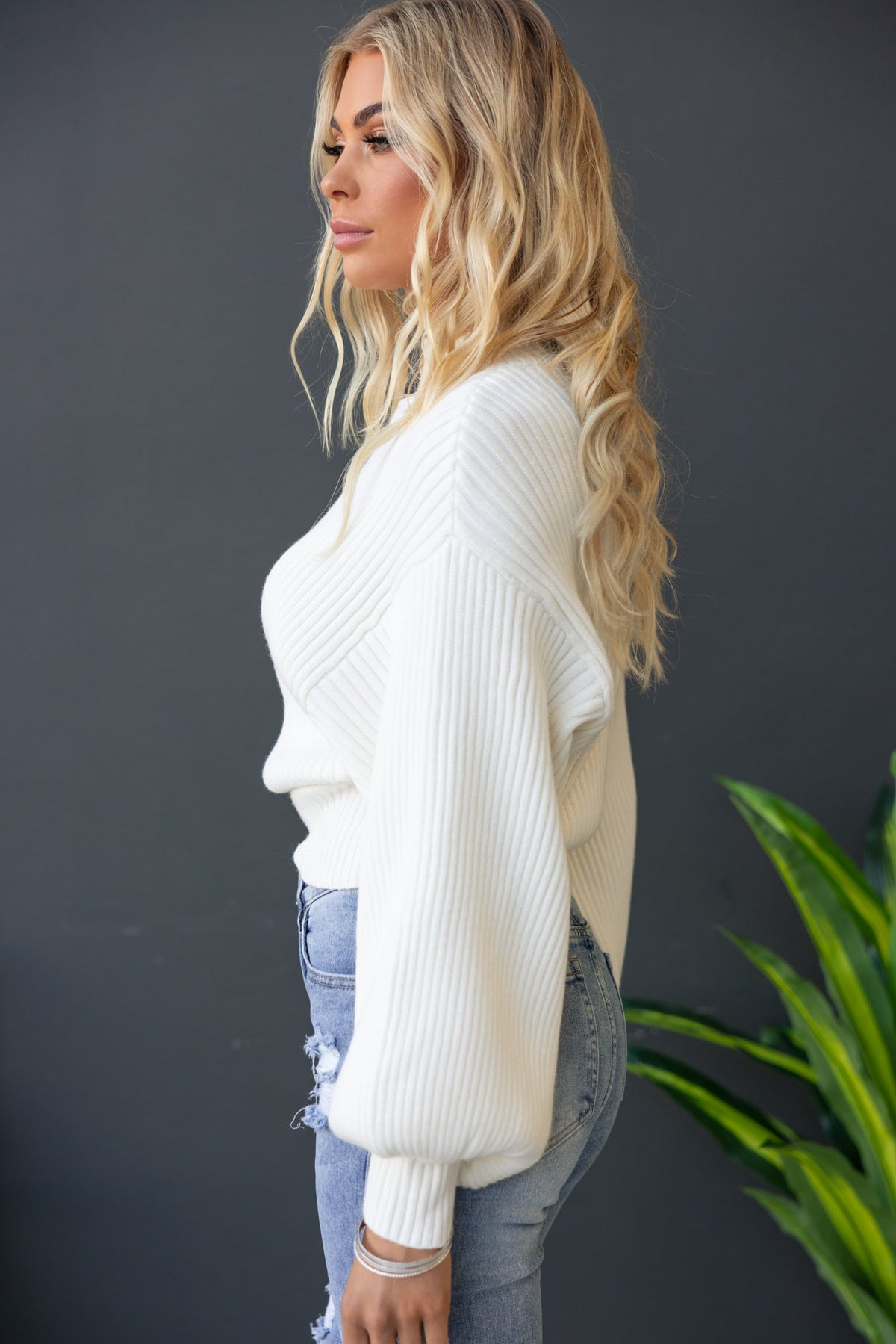 Model wearing Sola Jumper with mock neckline and wide sleeves in white ribbed knit against a neutral backdrop.
