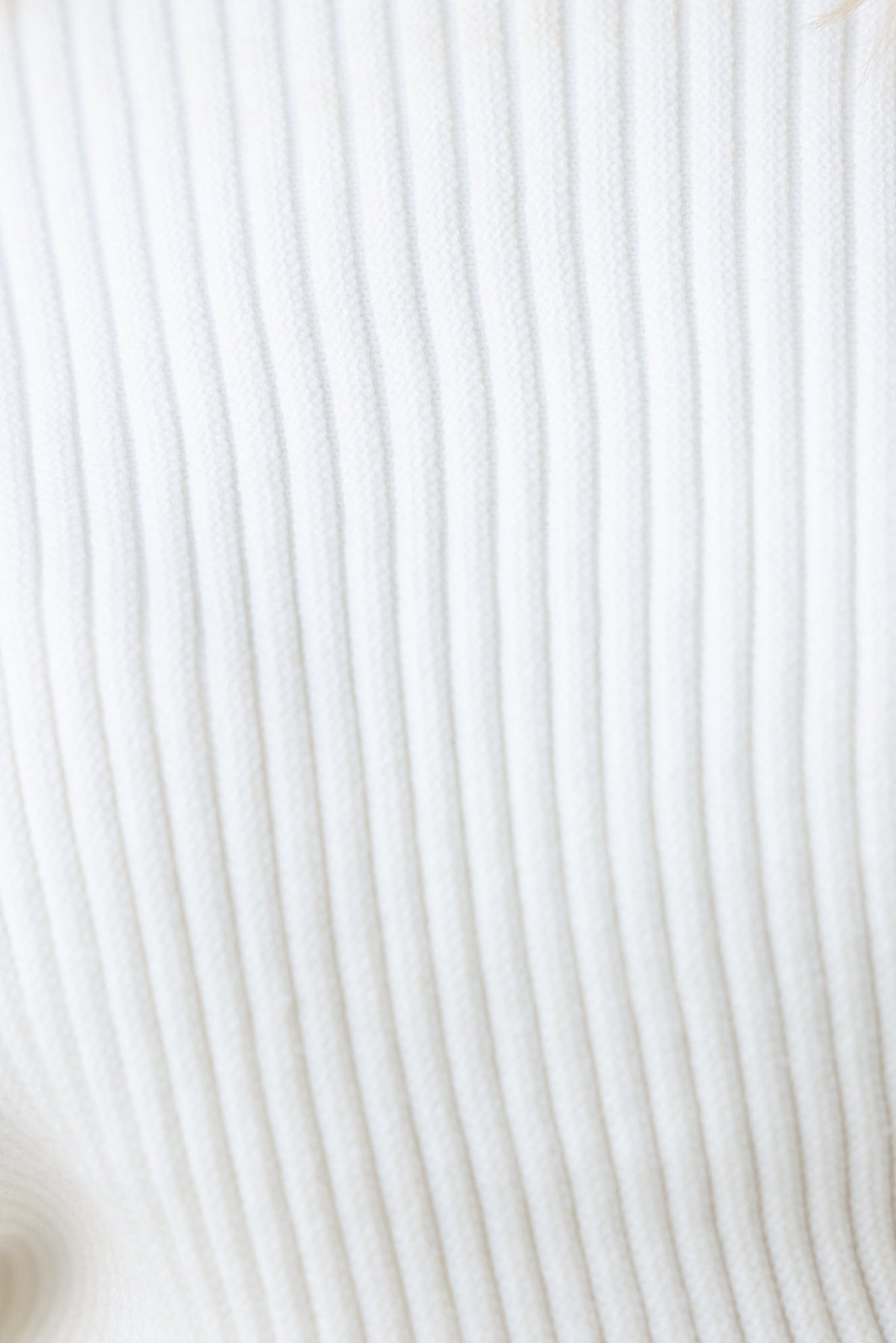 Close-up of textured ribbed knit fabric in white, highlighting the softness and stretch of the Sola Jumper.