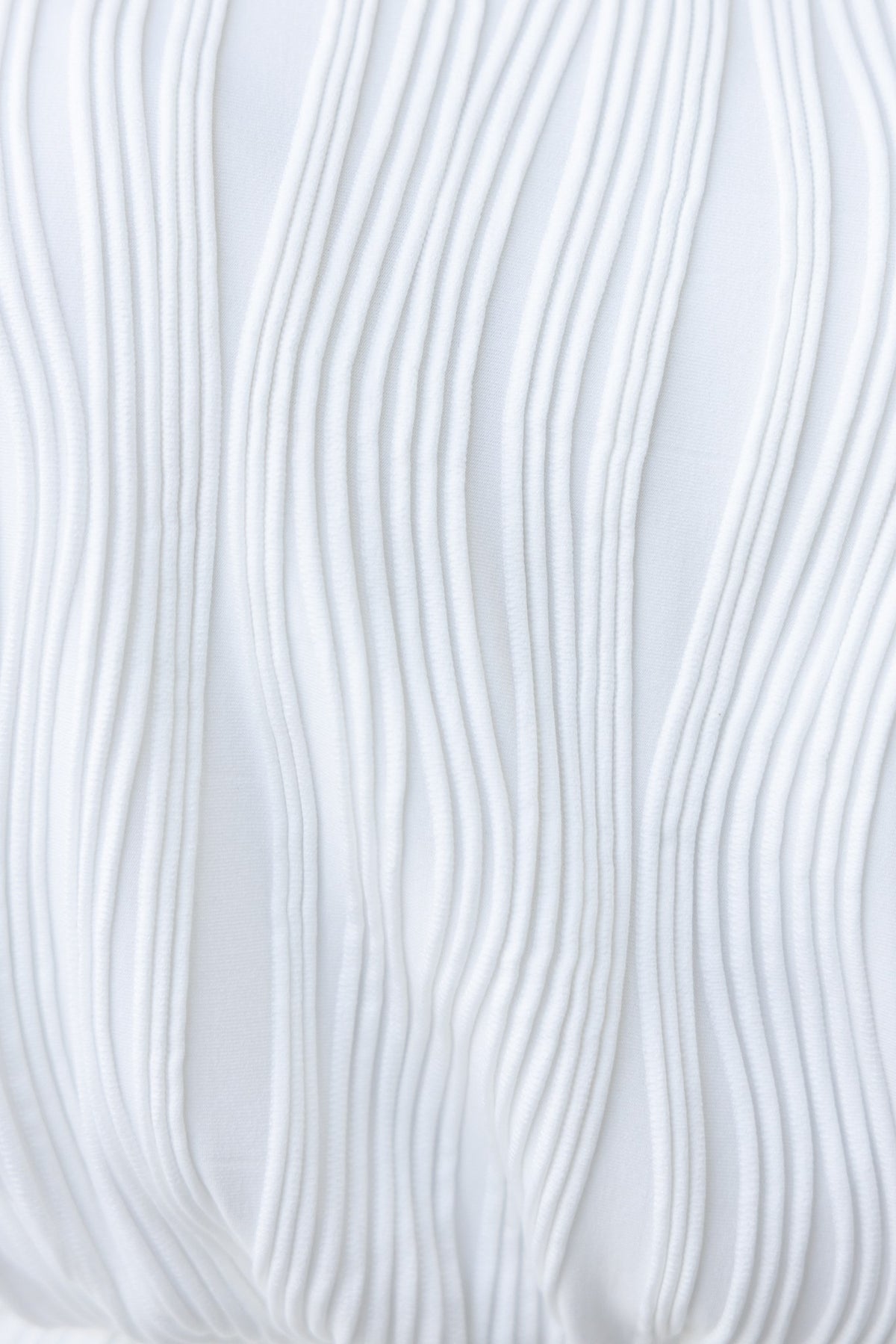 Close-up of textured white fabric with wavy lines, showcasing stylish design for the Jasper Dress.