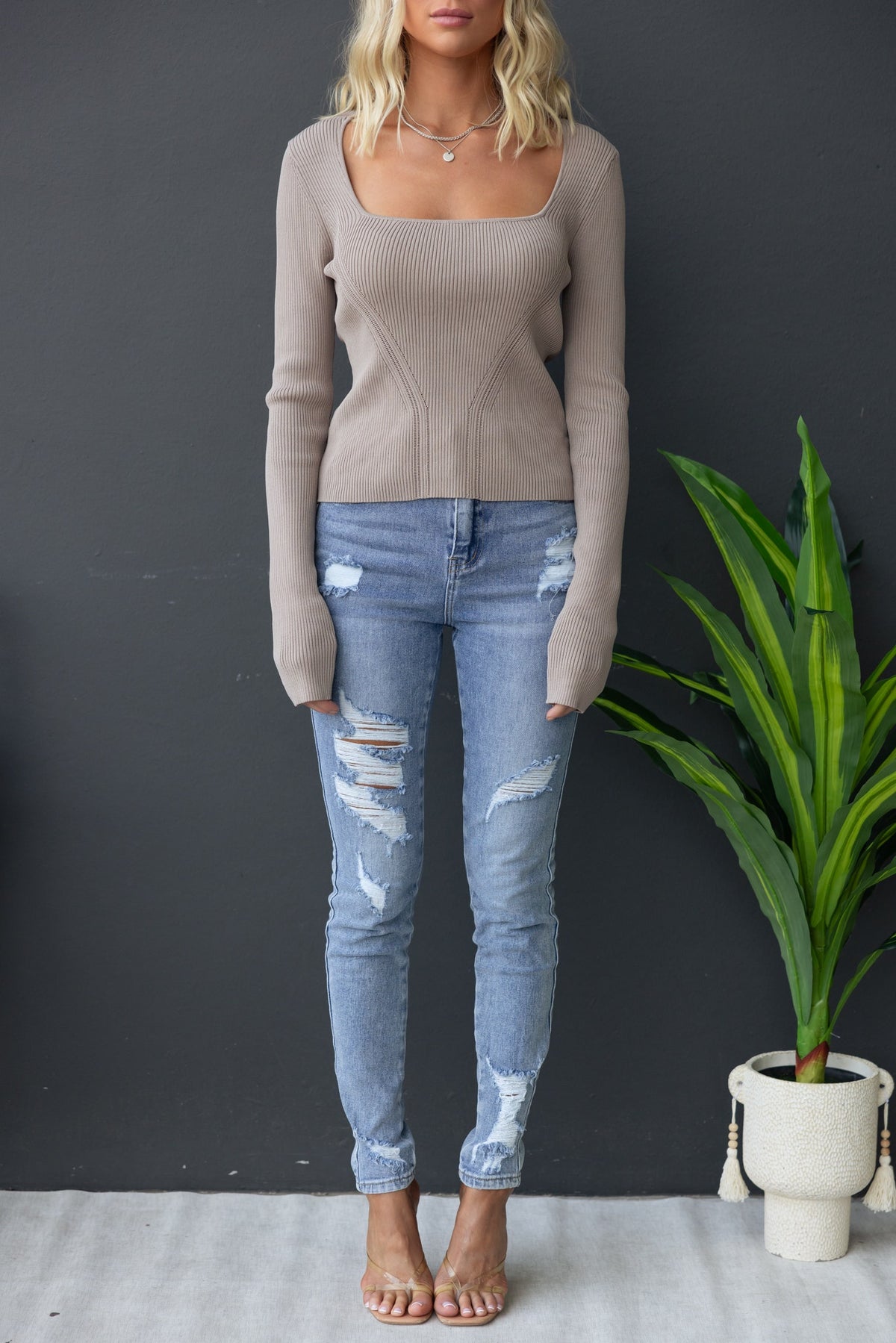 Model wearing Orber Top with square neckline, ribbed knit, paired with distressed jeans in a stylish setting.