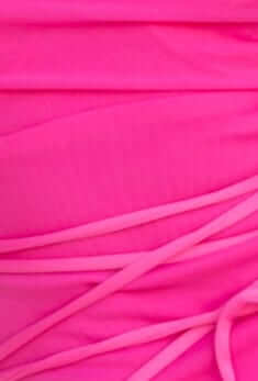 Close-up of vibrant pink mesh fabric featuring soft draping and intricate strap details for a tropical maxi dress.