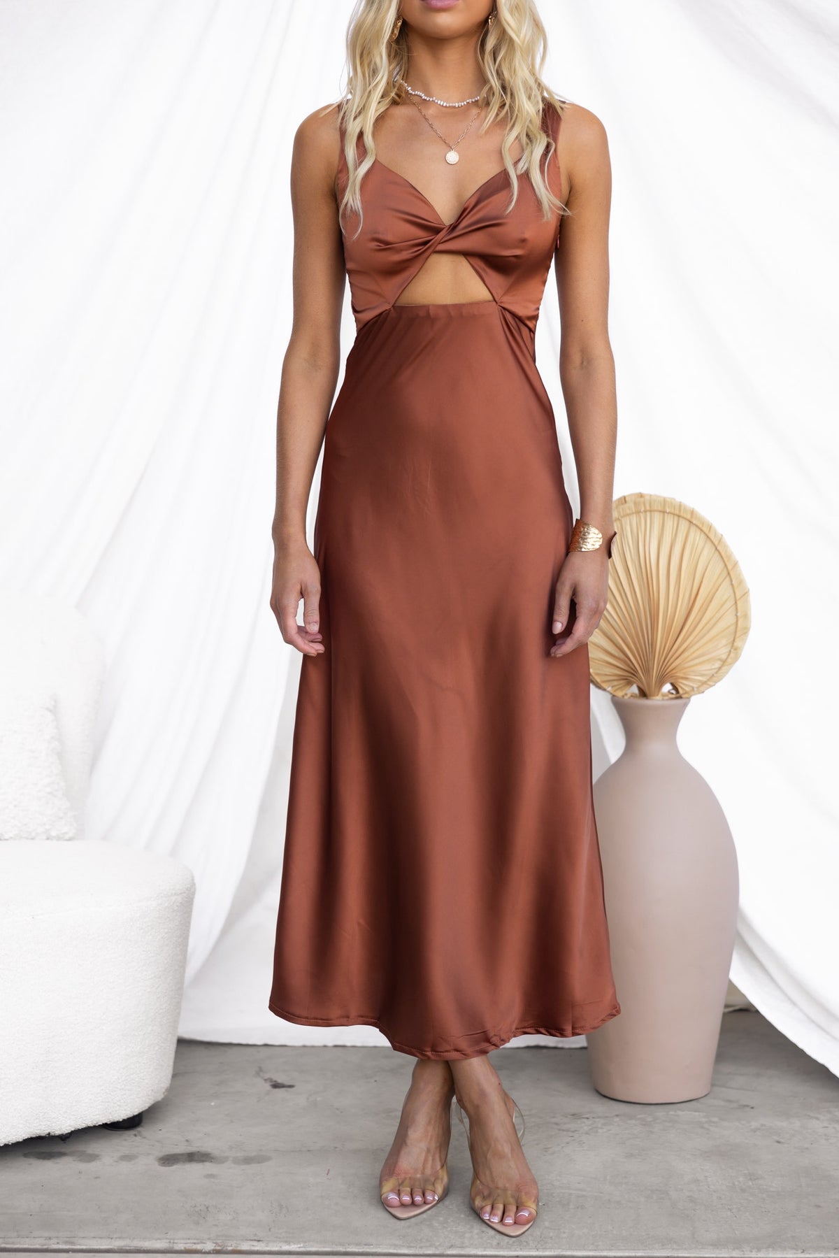 Aerida Midi Dress in rich brown satin with V-neckline and cut-out design, styled with elegant accessories.