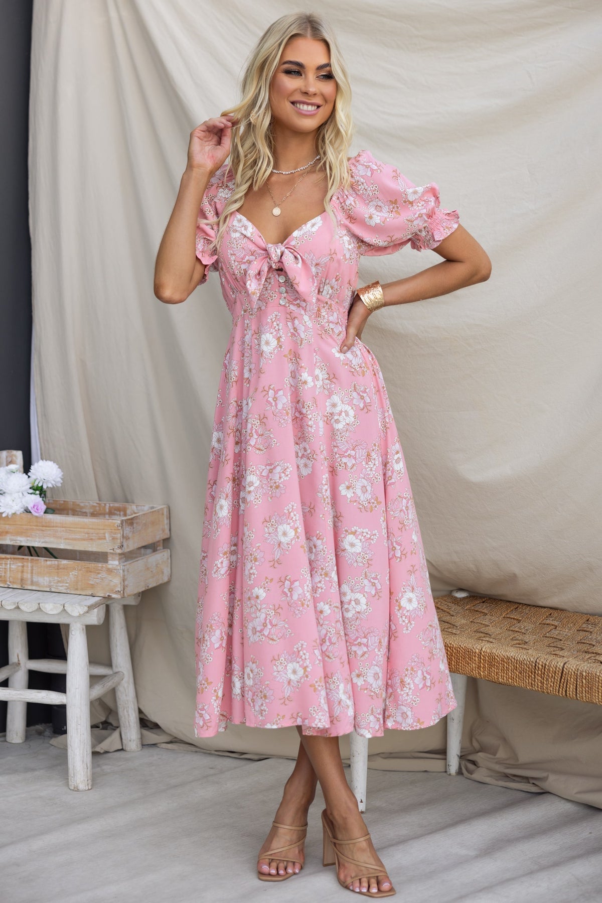 Rayanna Midi Dress in pink with floral print, featuring tie bust, elastic sleeves, and a flowing silhouette.