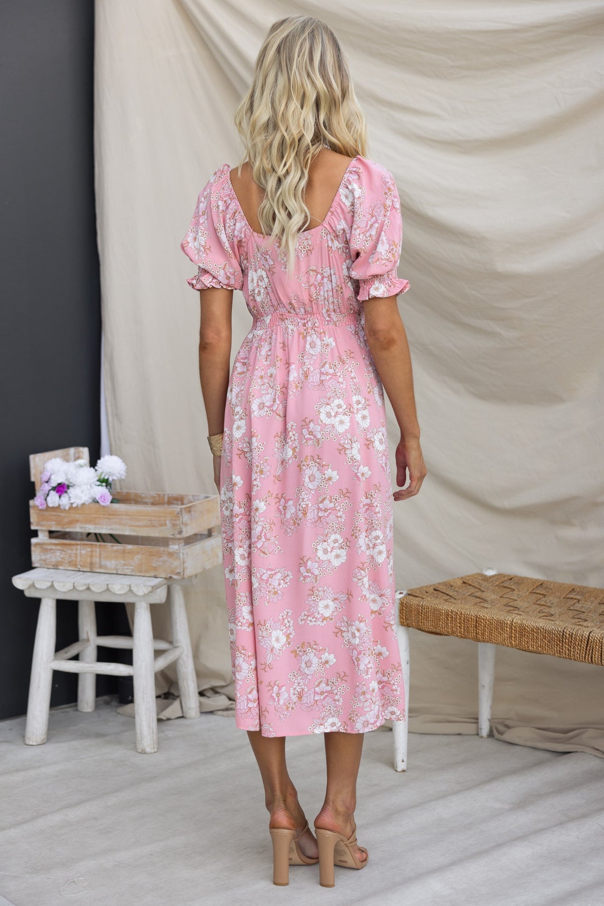 Back view of a woman in a floral Rayanna Midi Dress, featuring puff sleeves and a cinched waist.