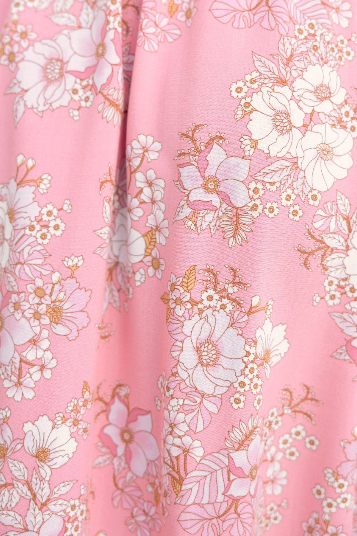 Close-up of floral print on Rayanna Midi Dress with pink background and intricate white and gold flower designs.
