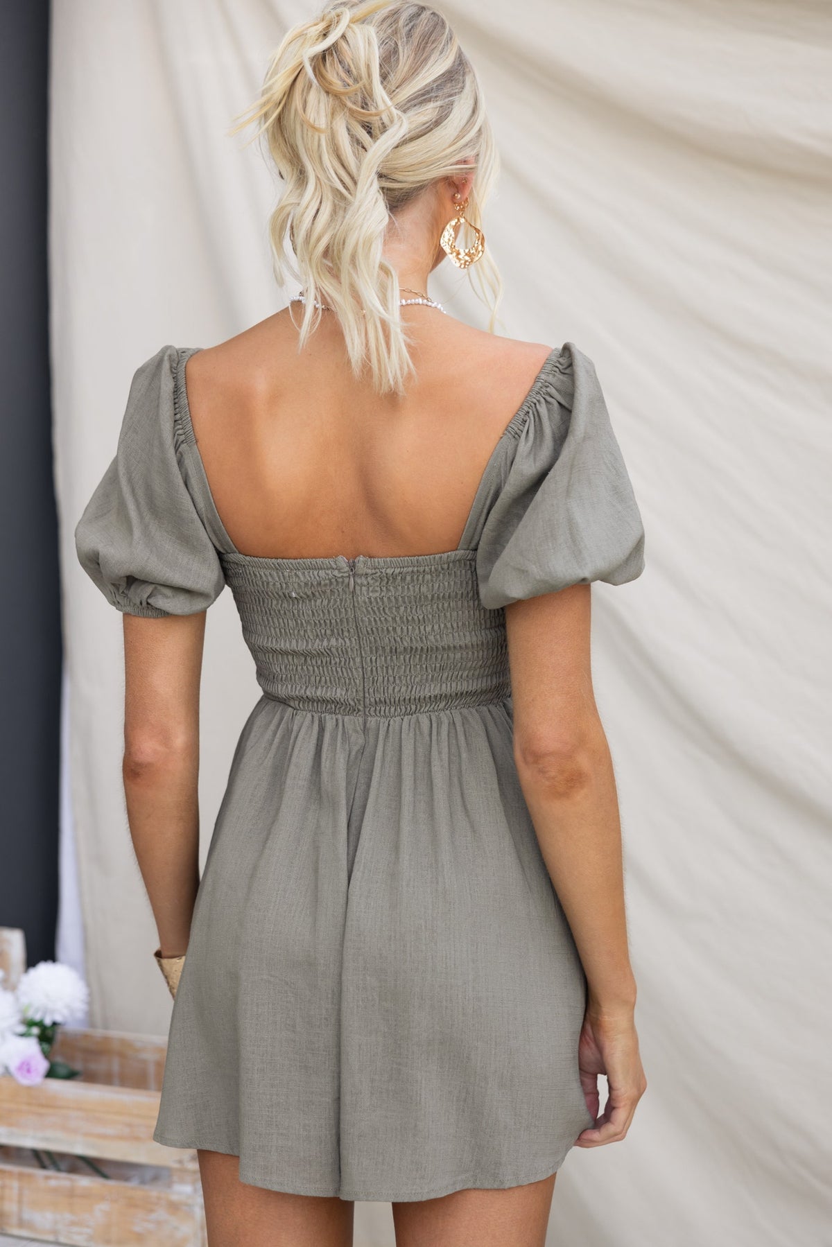 Back view of a model wearing the Kippy Playsuit with square neckline and puff sleeves in a soft linen fabric.