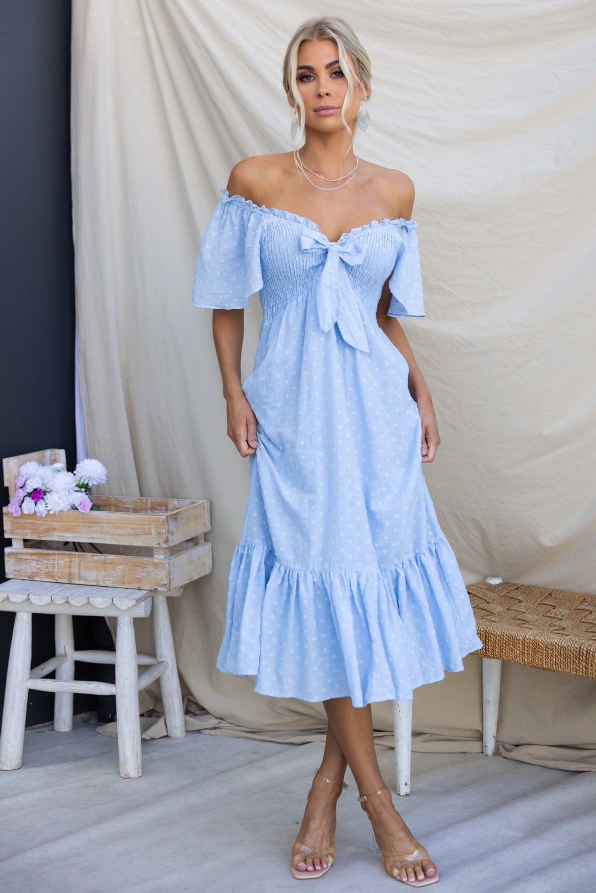 Angelis Midi Dress in light blue with off-the-shoulder sleeves and tie at bust, featuring a textured cotton material.