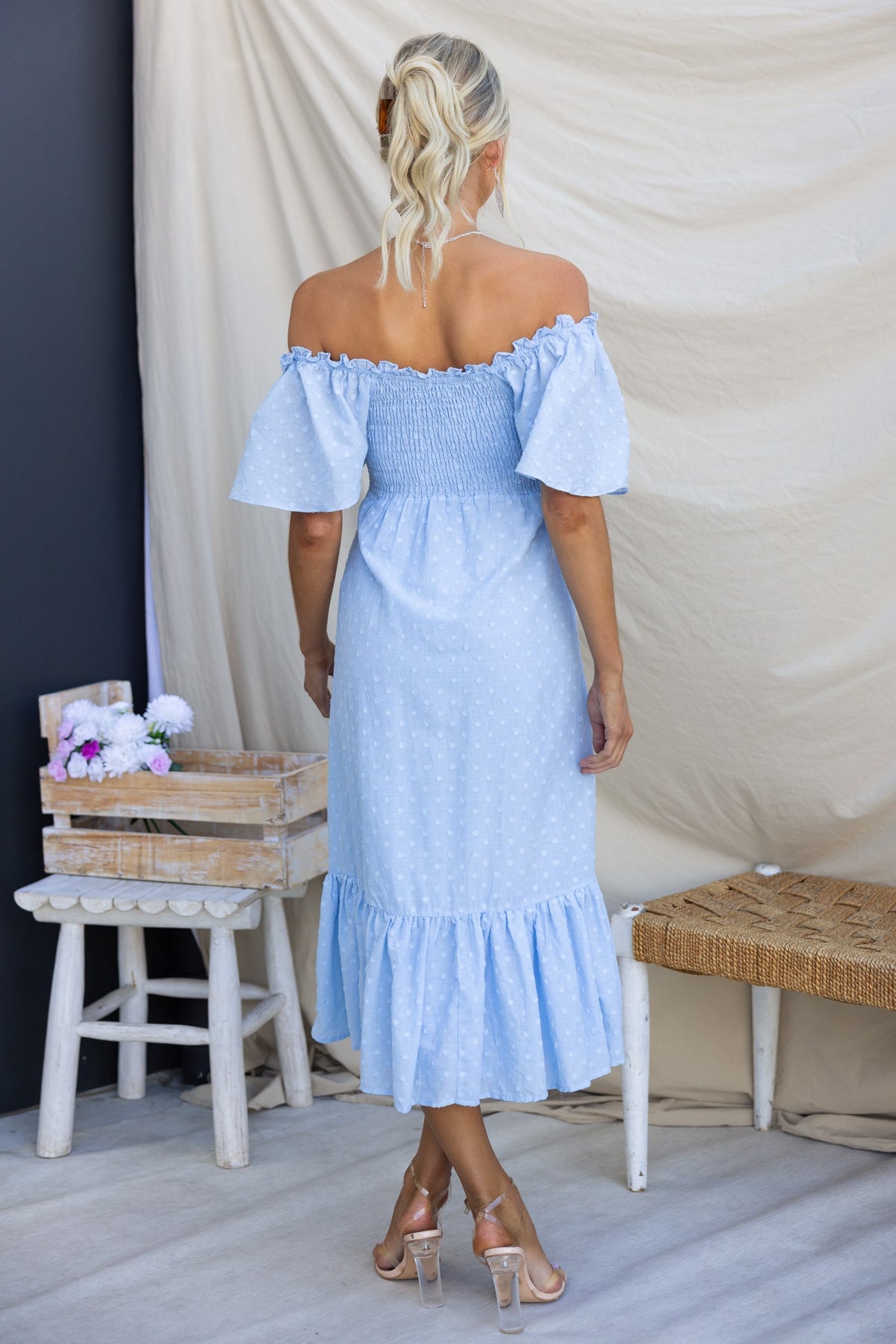 Light blue Angelis midi dress with off-the-shoulder sleeves and ruffled hem, styled for a summer look.