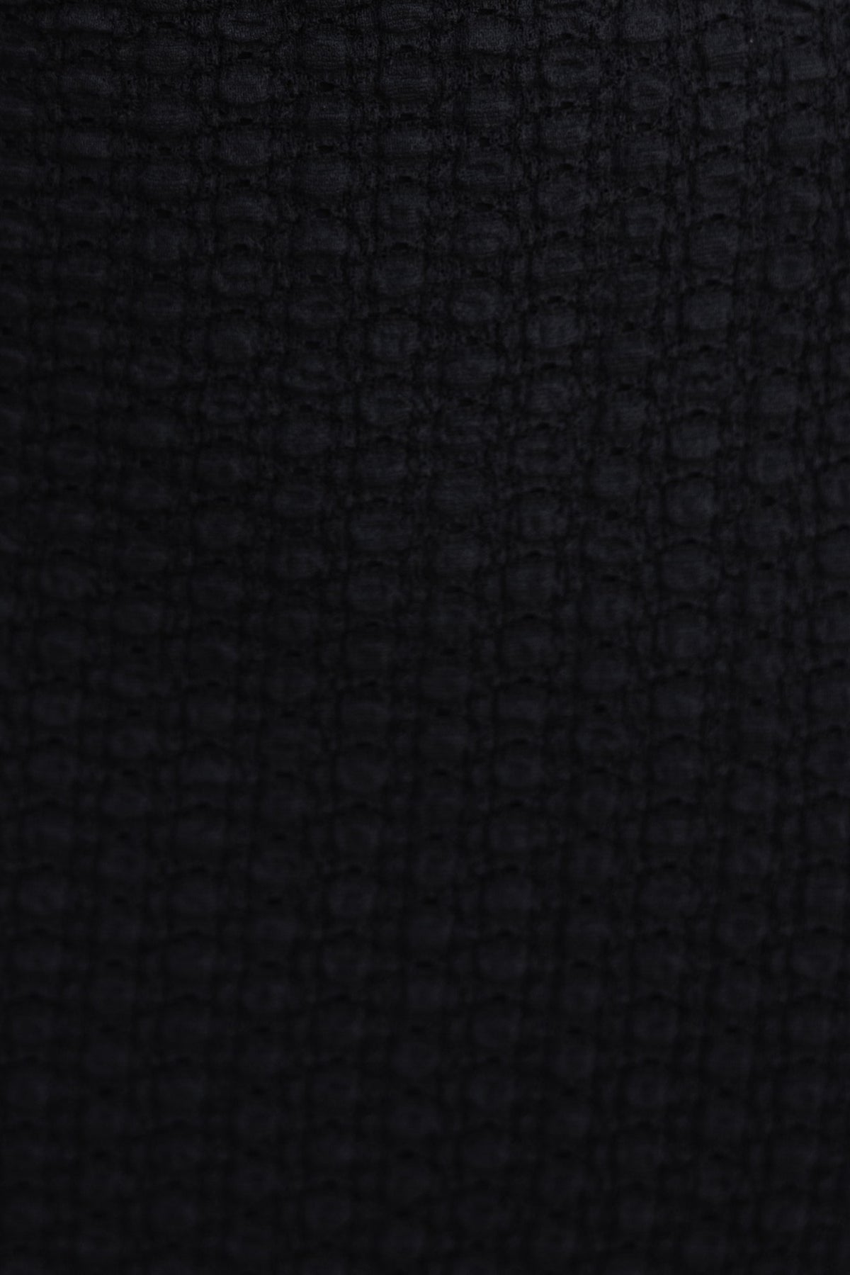 Close-up of textured black fabric featuring a subtle pattern, perfect for stylish tops.