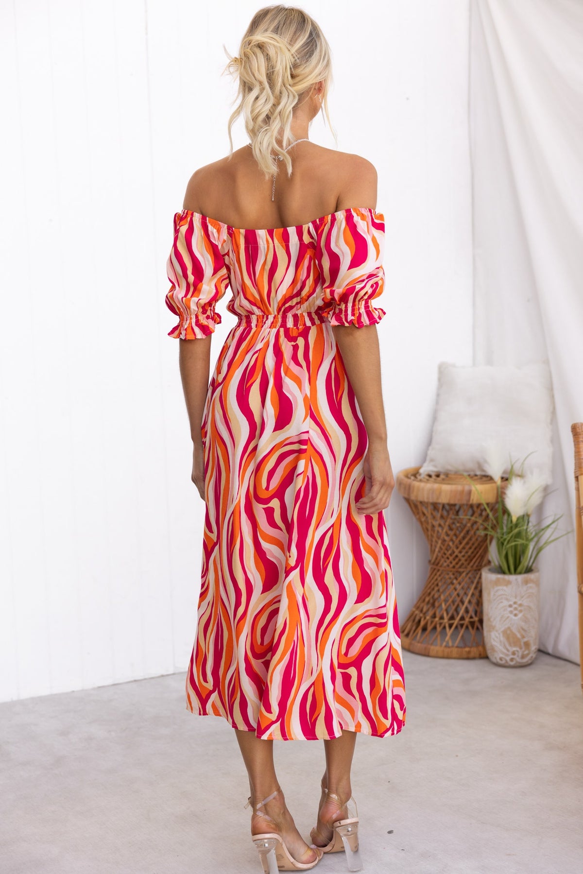 Back view of a woman in a colorful Rayanna Midi Dress with off-shoulder sleeves and swirling patterns.