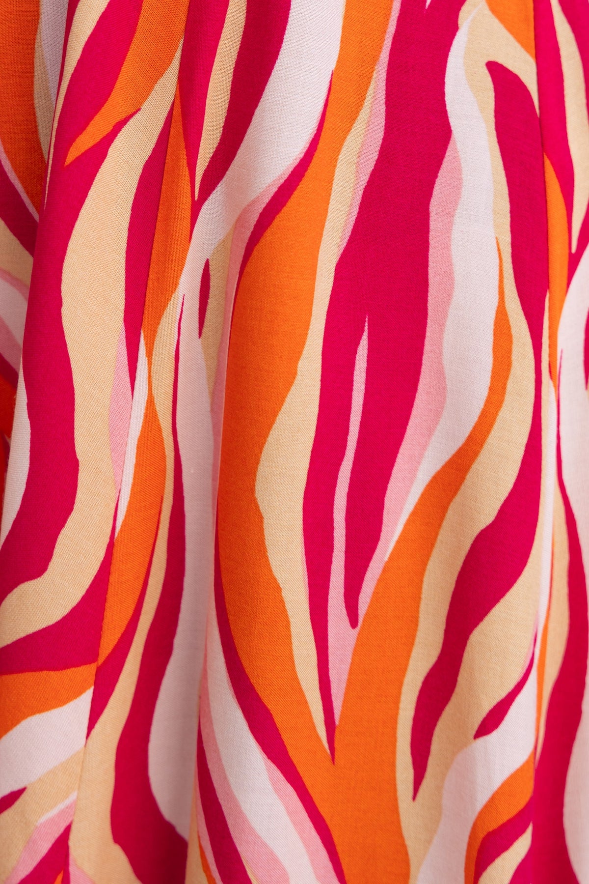 Close-up of vibrant pink, orange, and cream abstract pattern on fabric of the Rayanna Midi Dress.