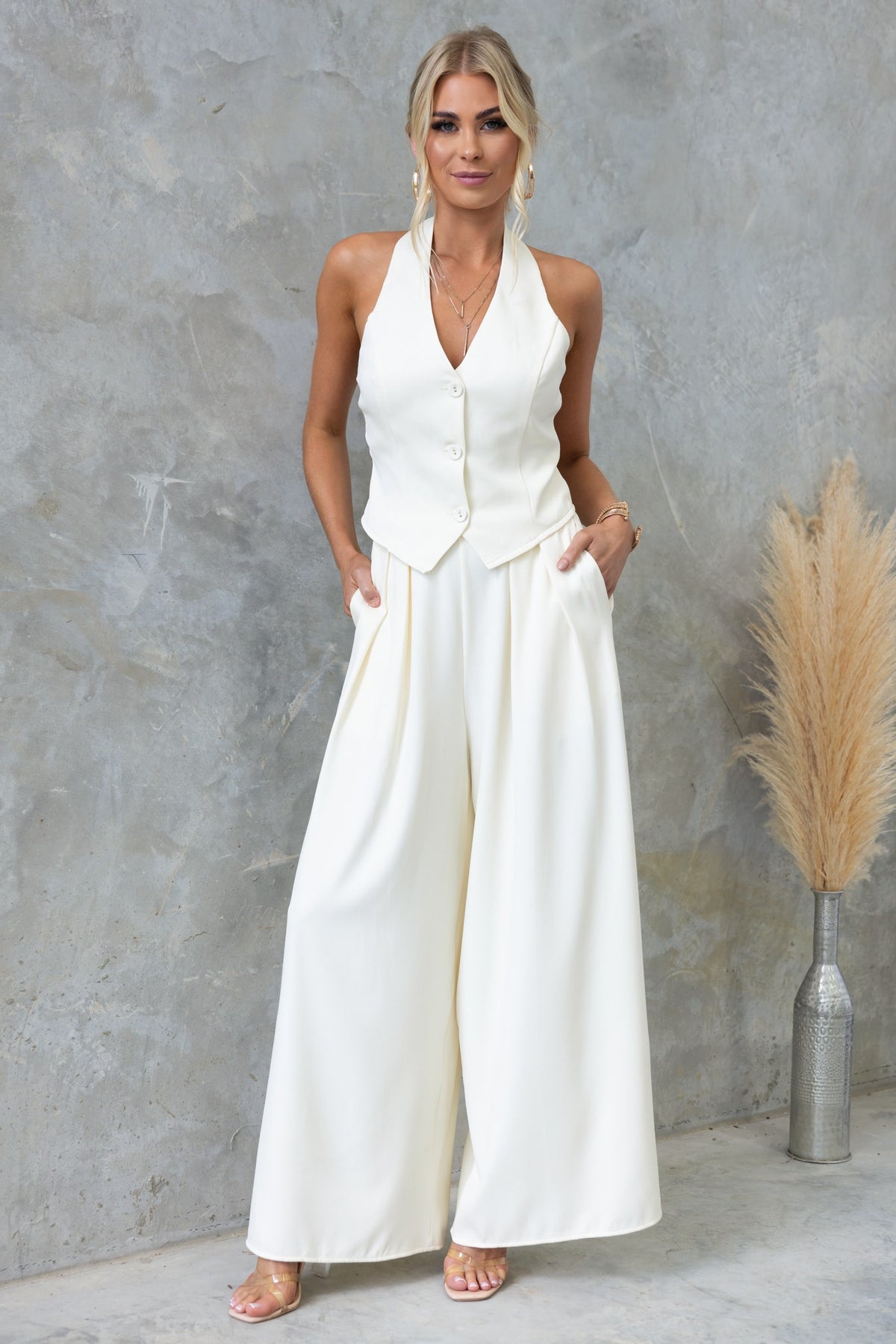 Model wearing the Kamala Top, a white vest-style top with a V-neckline and wide-leg pants, showcasing a stylish outfit.