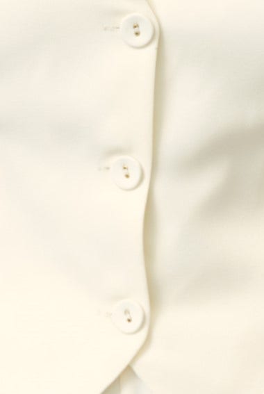 Close-up of Kamala Top featuring button-up detail in cream color with smooth fabric and V-neckline.