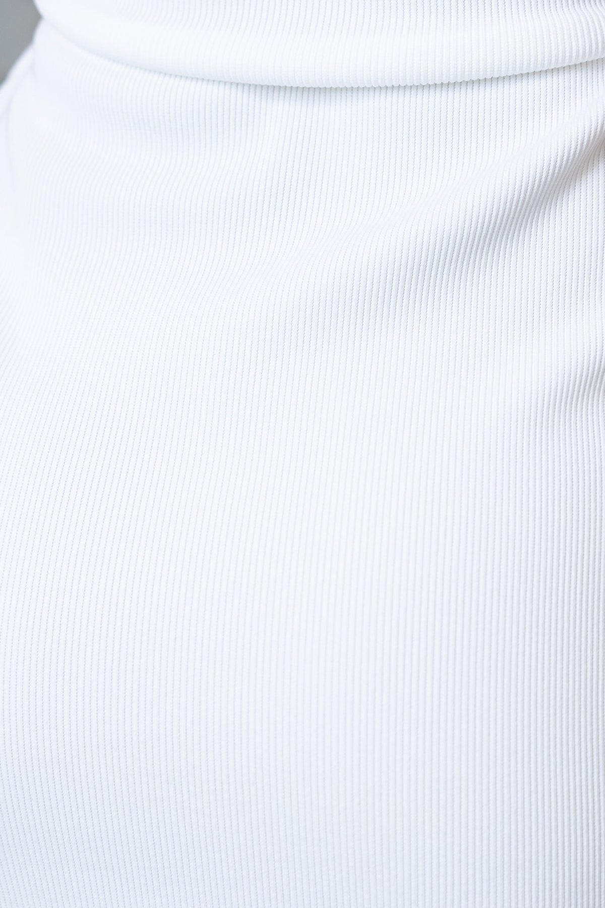 Close-up of ribbed white fabric showcasing texture, ideal for fashion items like dresses.