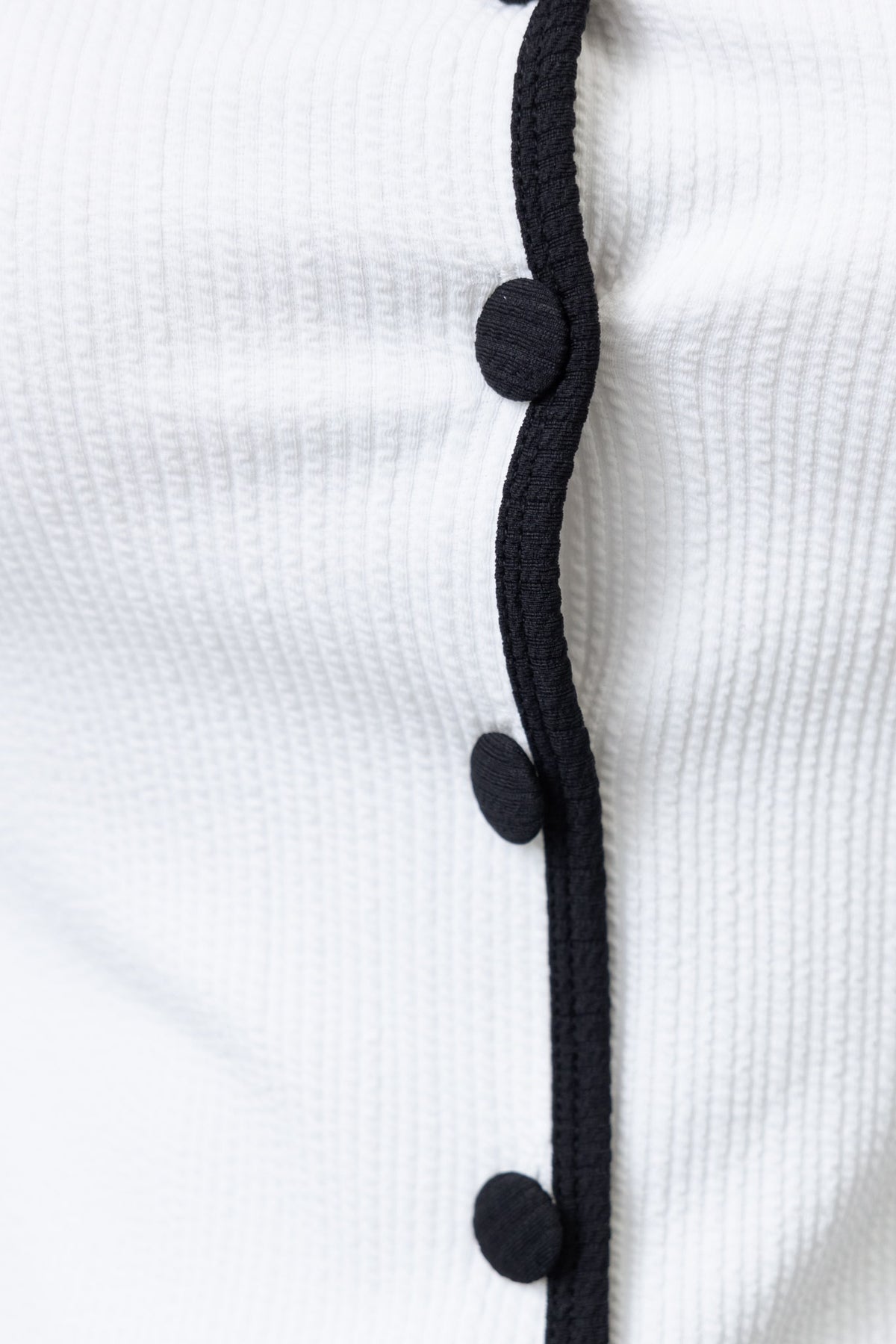 Close-up of Danaro Dress showing round neckline, button-up front detail, and textured material.