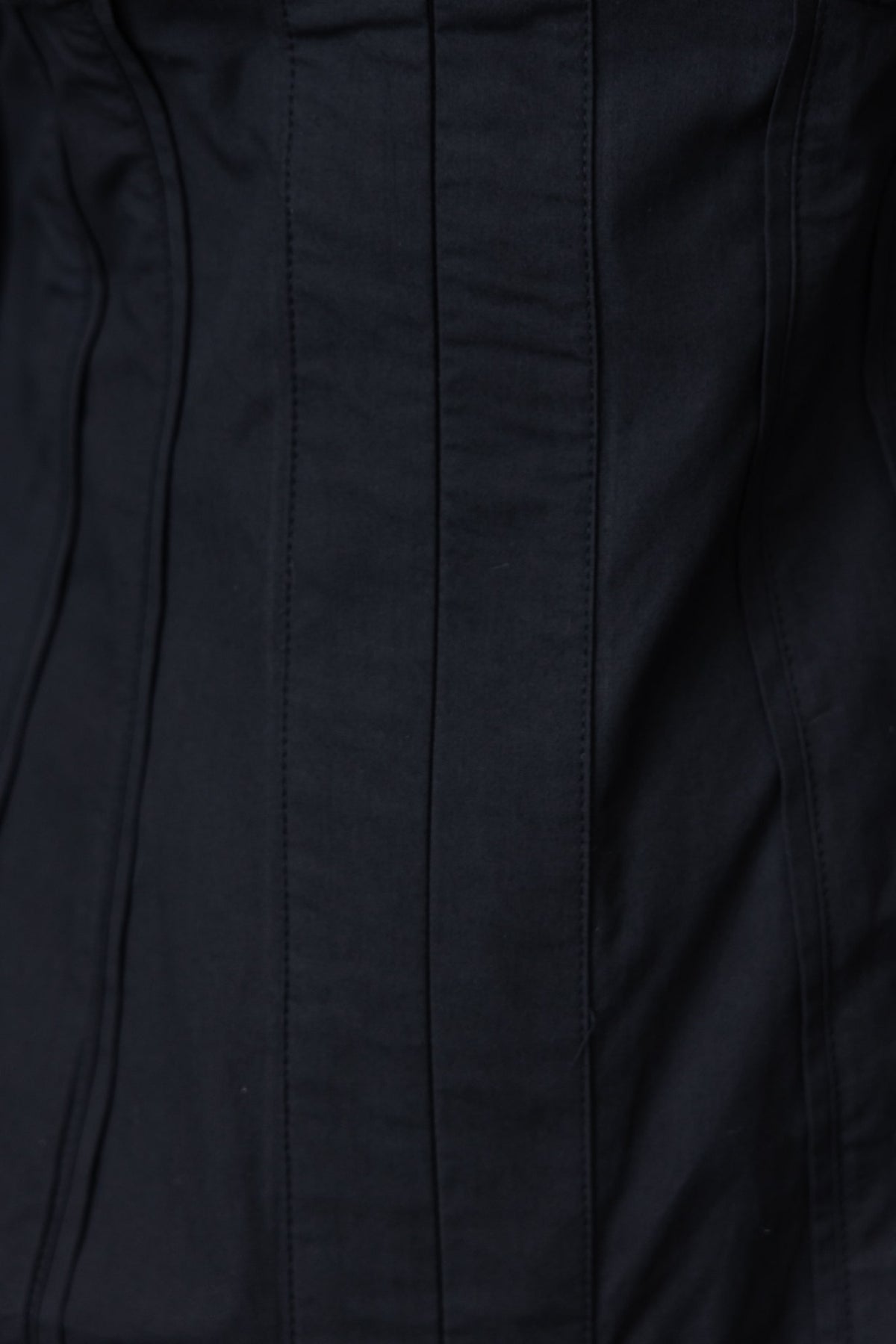 Close-up of the textured fabric detail of a black Lanetta Dress, highlighting its structured panels and smooth finish.