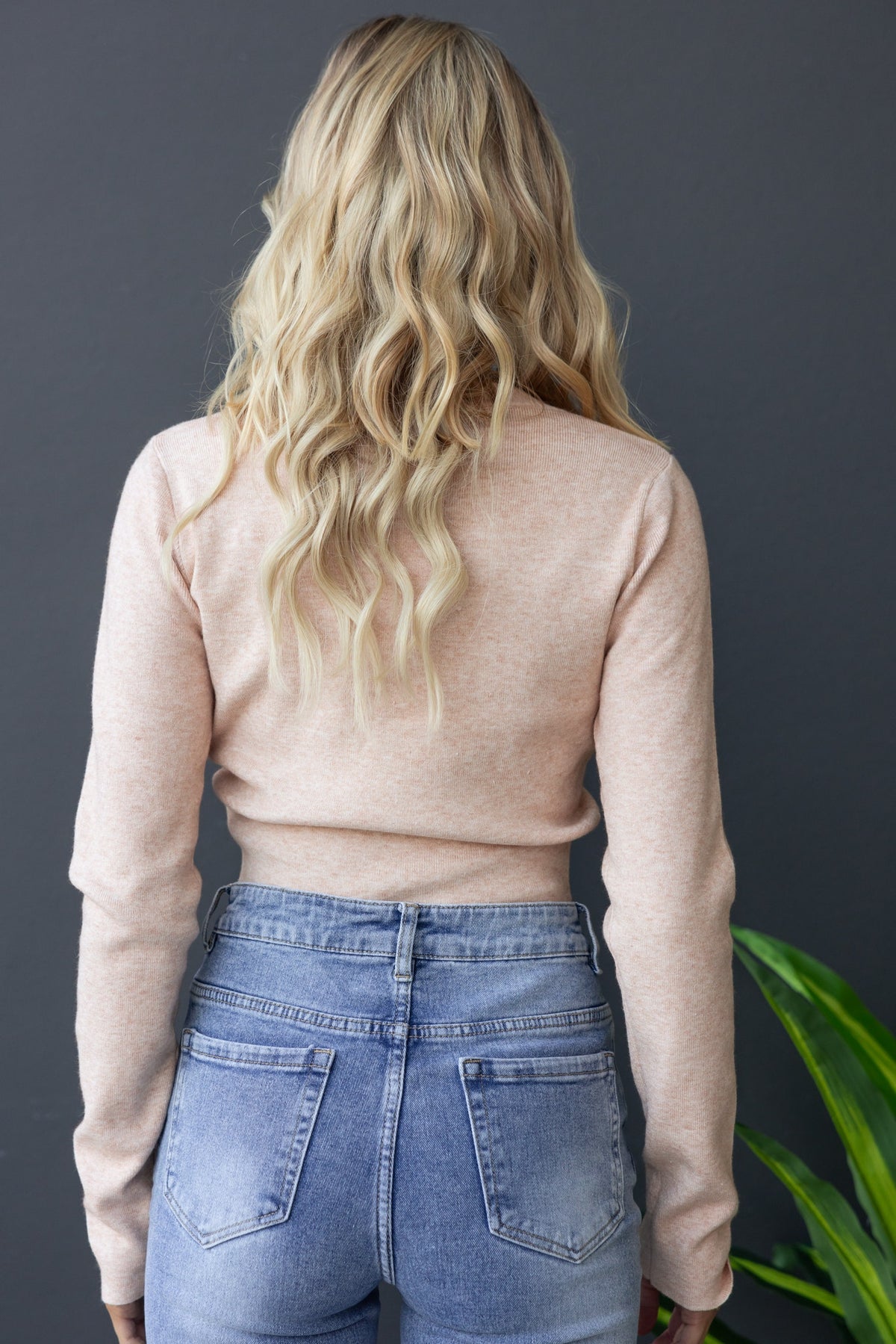 Back view of a woman in a ribbed knit Maura top and high-waisted jeans, showcasing casual style and soft fabric.