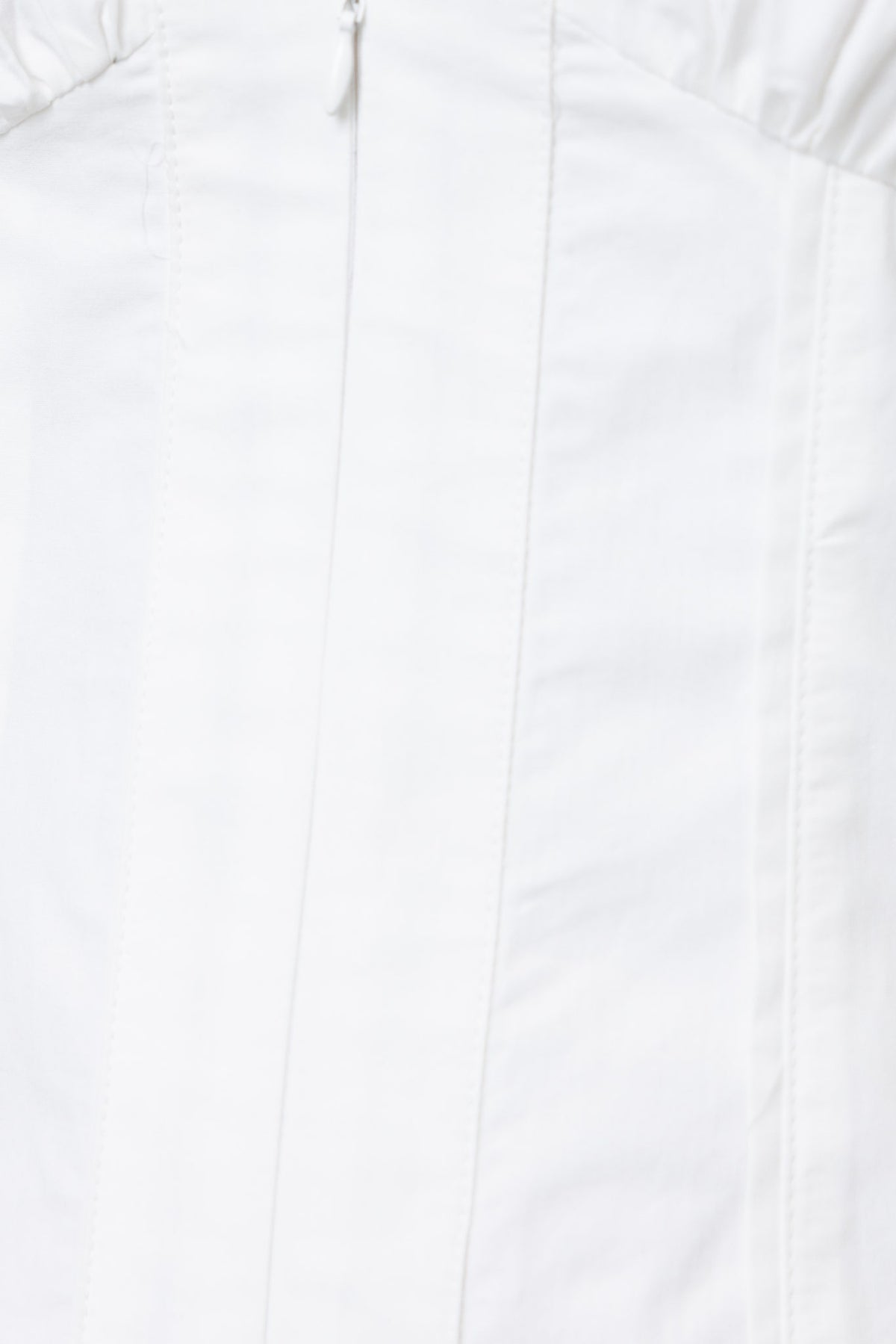 Close-up of the Lanetta Dress featuring a white fabric, V-neckline, and front zipper detail, ideal for summer styling.