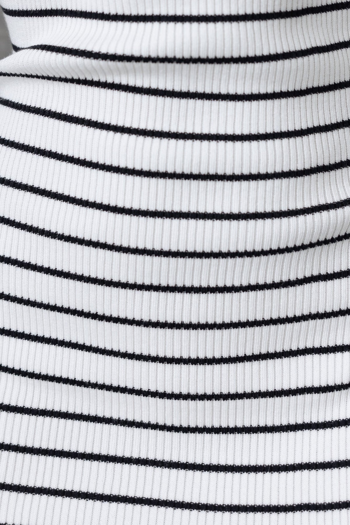 Close-up of ribbed knit fabric featuring black and white stripes, suitable for a trendy midi dress.