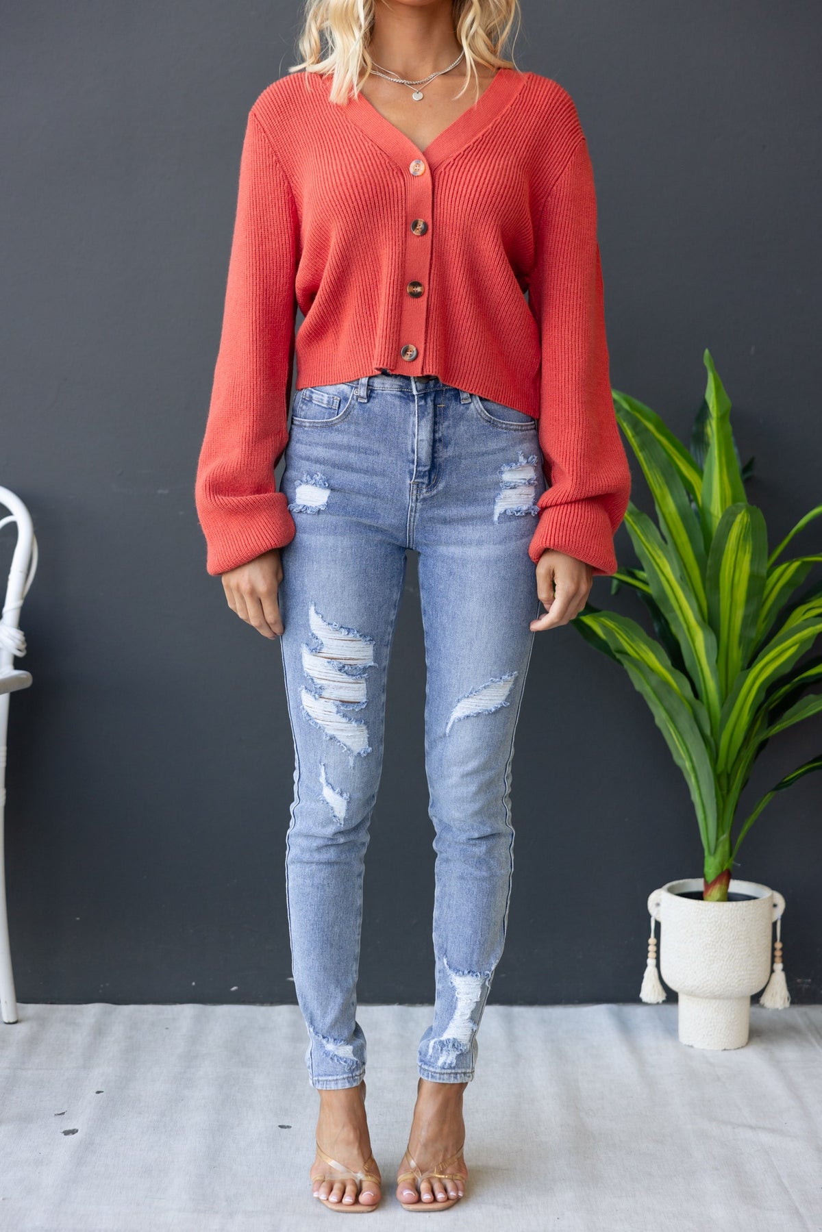 Modalla Cardigan in coral with V-neckline and button-up front, paired with distressed skinny jeans.