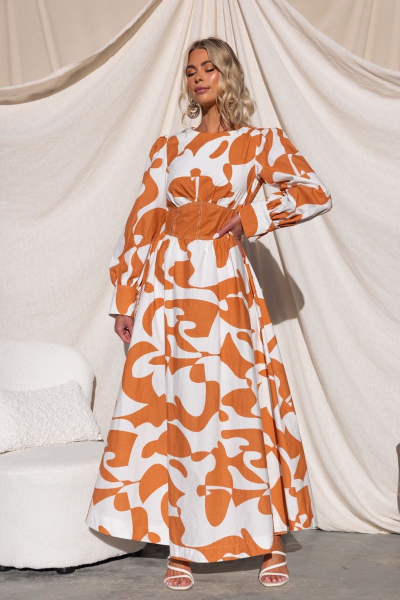 Bohemia maxi dress featuring an orange and white abstract pattern, with a round neckline and long puffed sleeves.