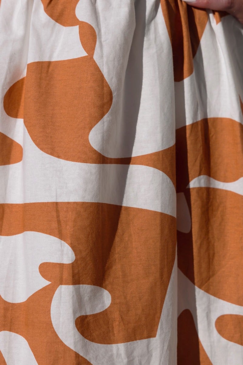 Close-up of textured cotton blend fabric featuring bold orange and white abstract patterns, perfect for a stylish Bohemia Maxi Dress.