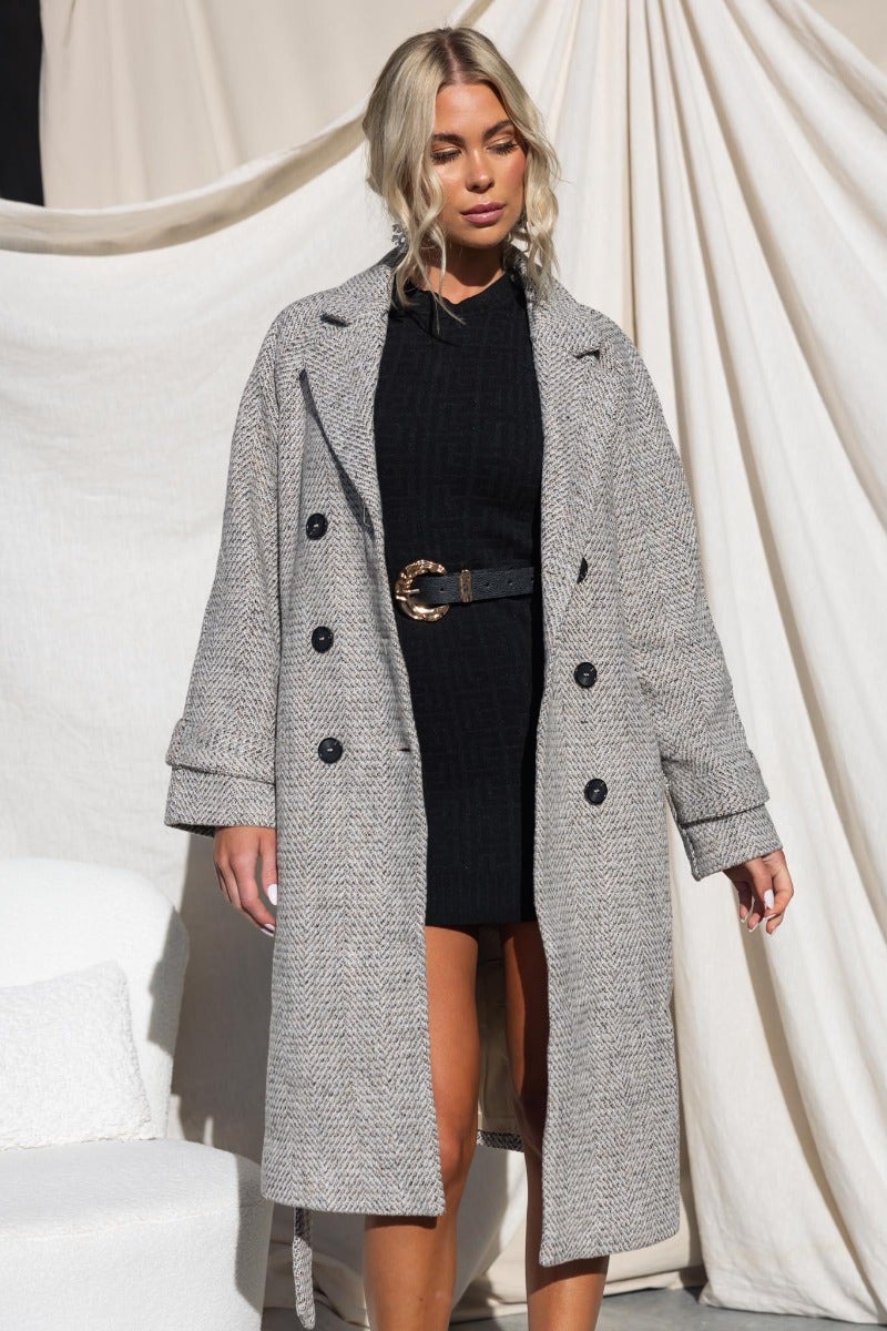 Atthow longline tweed coat featuring collar, lapel, button-up front, and removable belt. Styled with a black dress.
