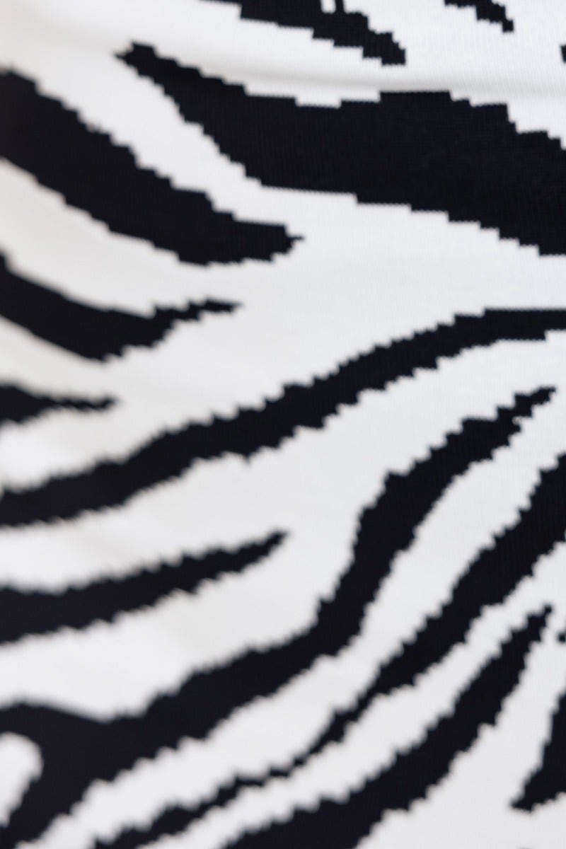 Close-up of zebra print pattern in black and white, featuring bold, contrasting stripes.