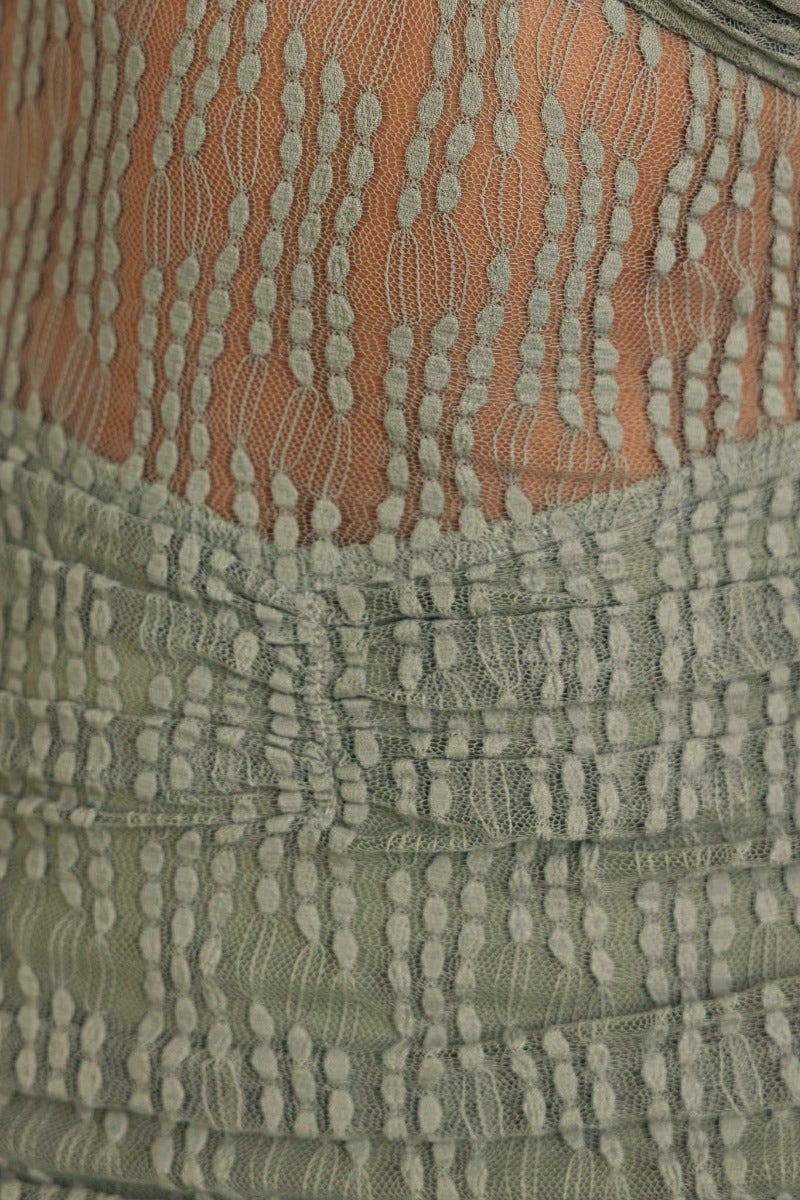 Close-up of textured mesh overlay and ruching detail on Xavina Maxi Dress in soft green fabric.