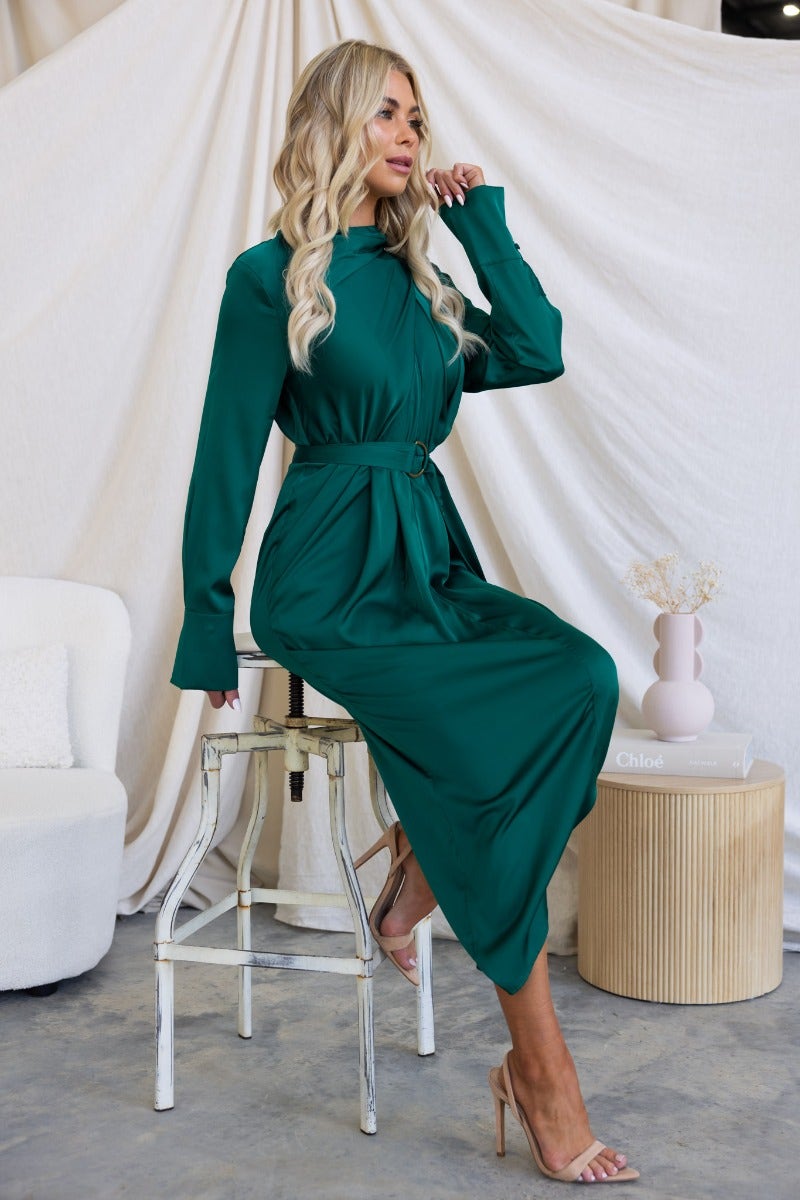 Model wearing a satin Maranta Midi Dress in deep green, featuring a high neckline and removable belt, styled elegantly.